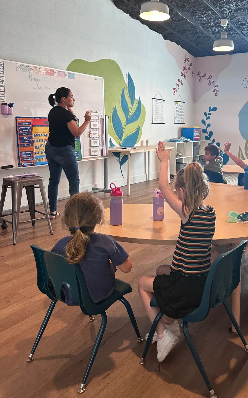 A teacher leading ROC Academy students in prayer during class